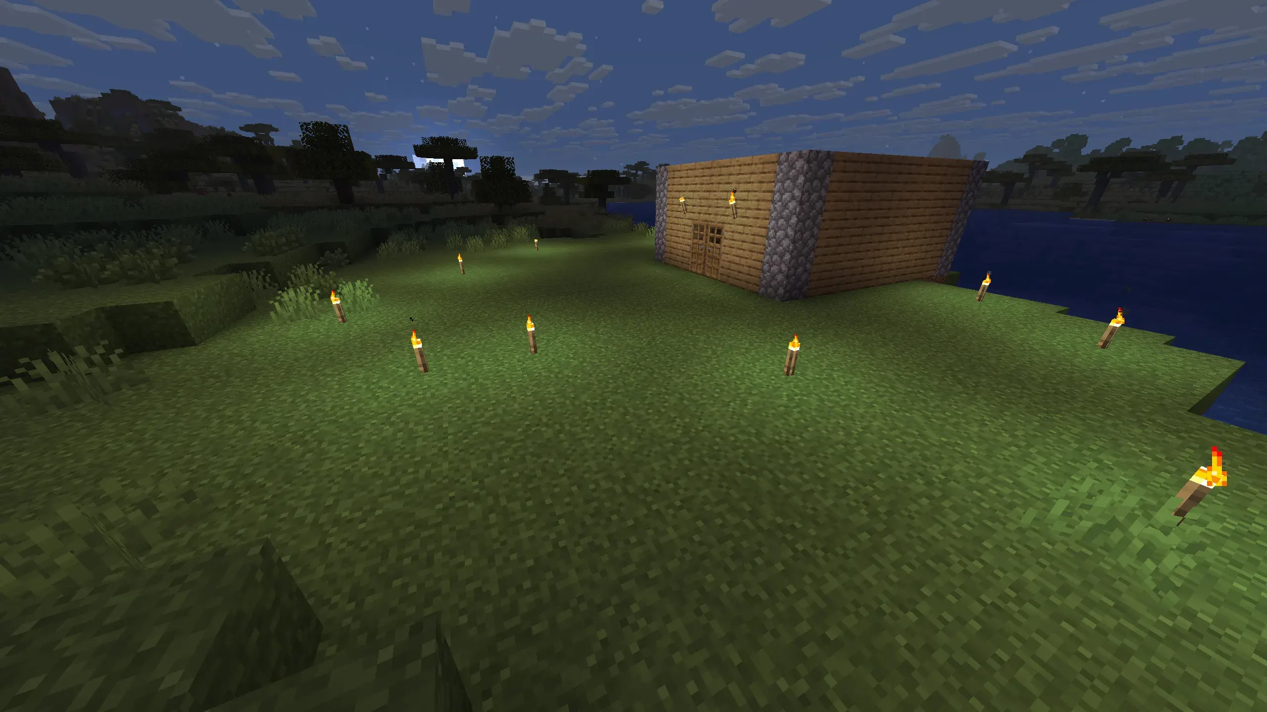 "Interior of a cozy Minecraft wooden starter base showing a bed, storage chest, furnace, and multiple wall-mounted torches, with wooden plank walls and ceiling."