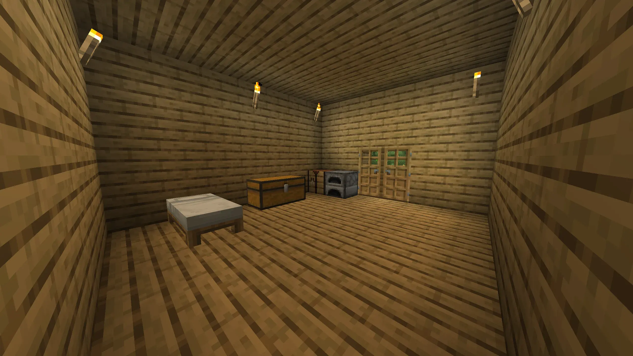 Interior of a cozy Minecraft wooden starter base showing a bed, storage chest, furnace, and multiple wall-mounted torches, with wooden plank walls and ceiling."
